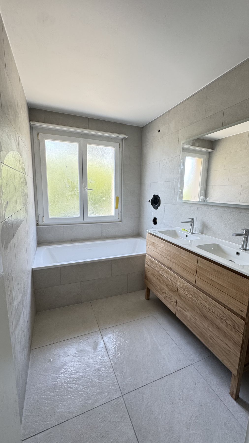 Salle de bain rénovée à Neuchâtel - carrelage grand format gris, baignoire et meuble double vasque bois